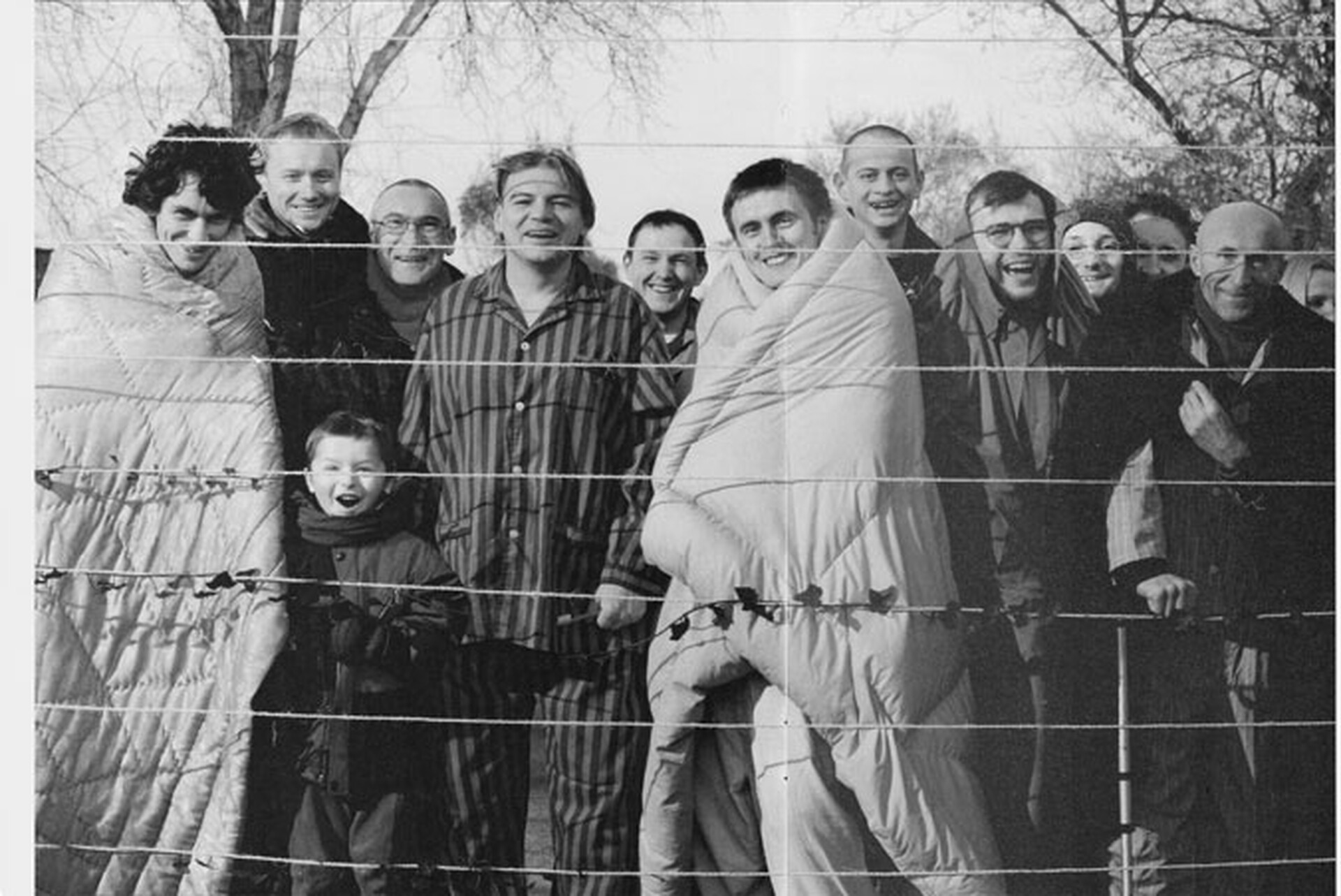  Czarno-białe zdjęcie Zbigniewa Libery Mieszkańcy z cyklu Pozytywy. Jest to zainscenizowana fotografia przedstawiająca kilkanaście uśmiechniętych osób pozujących z rozpiętymi sznurkami do wieszania prania. 